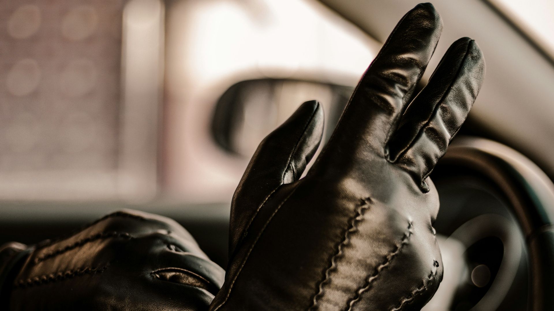 a man wearing black leather gloves driving a car