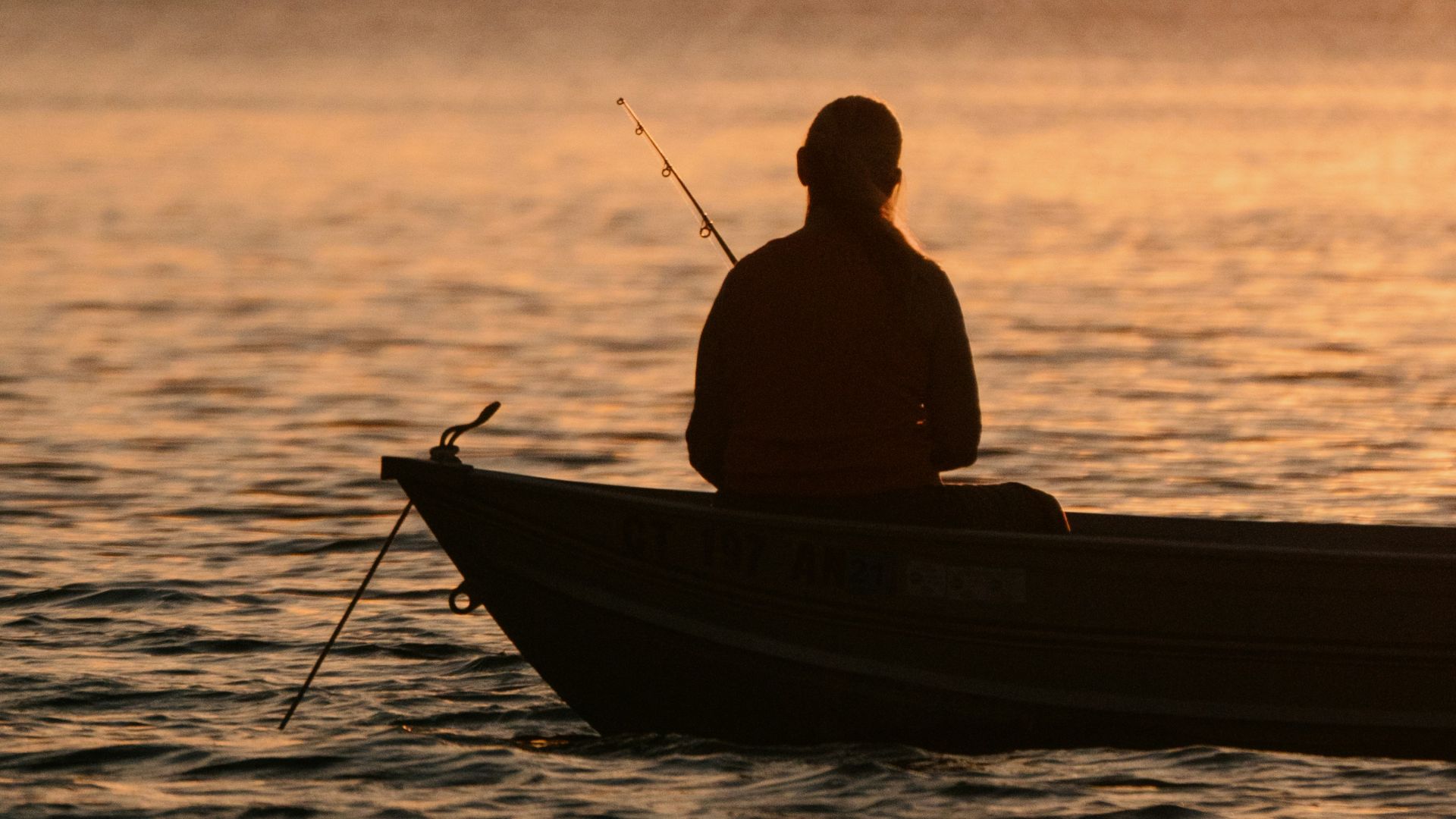 silhouette of man riding on boat during sunset