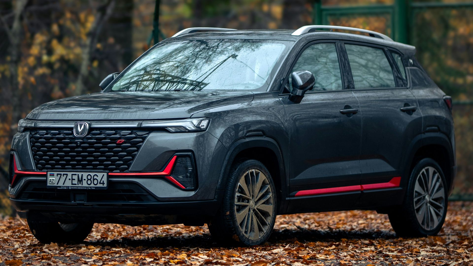 A black car parked in front of a fence