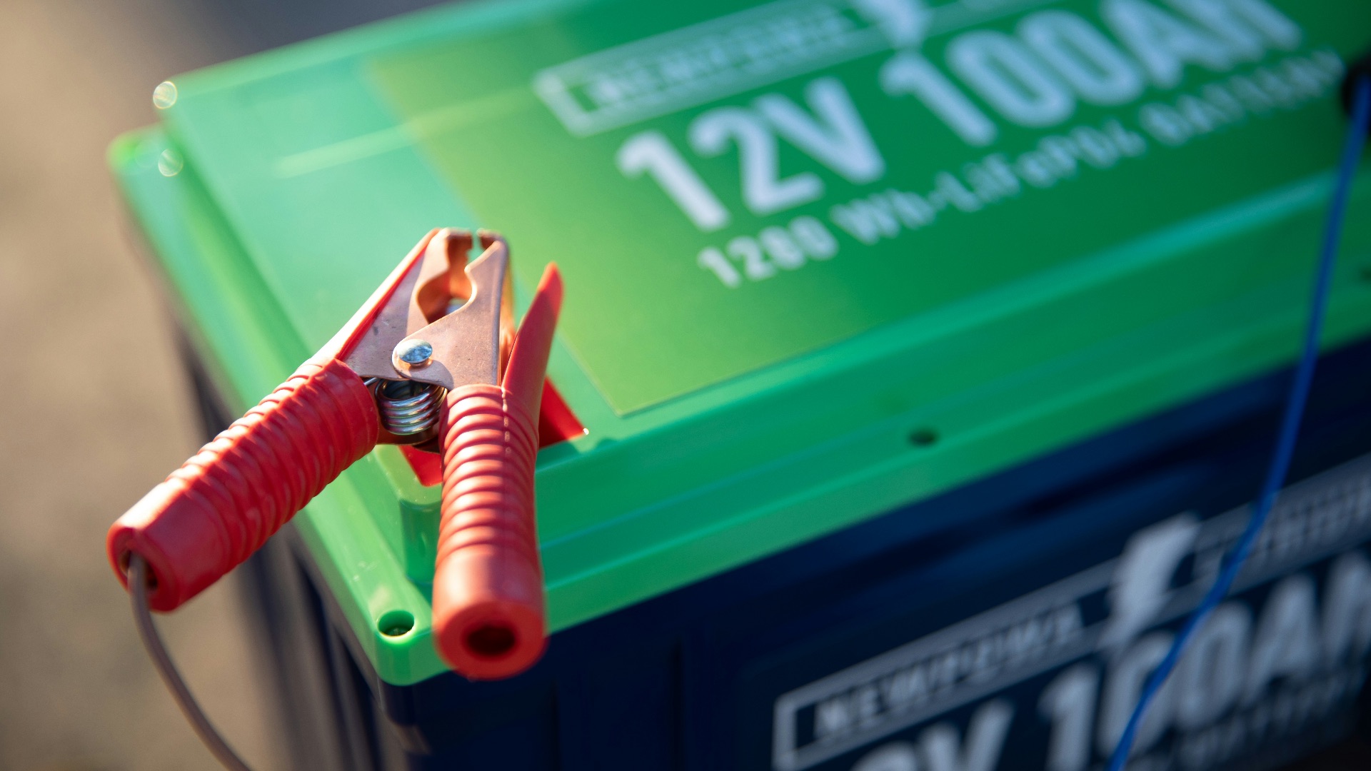 a red and green battery with a pair of pliers attached to it