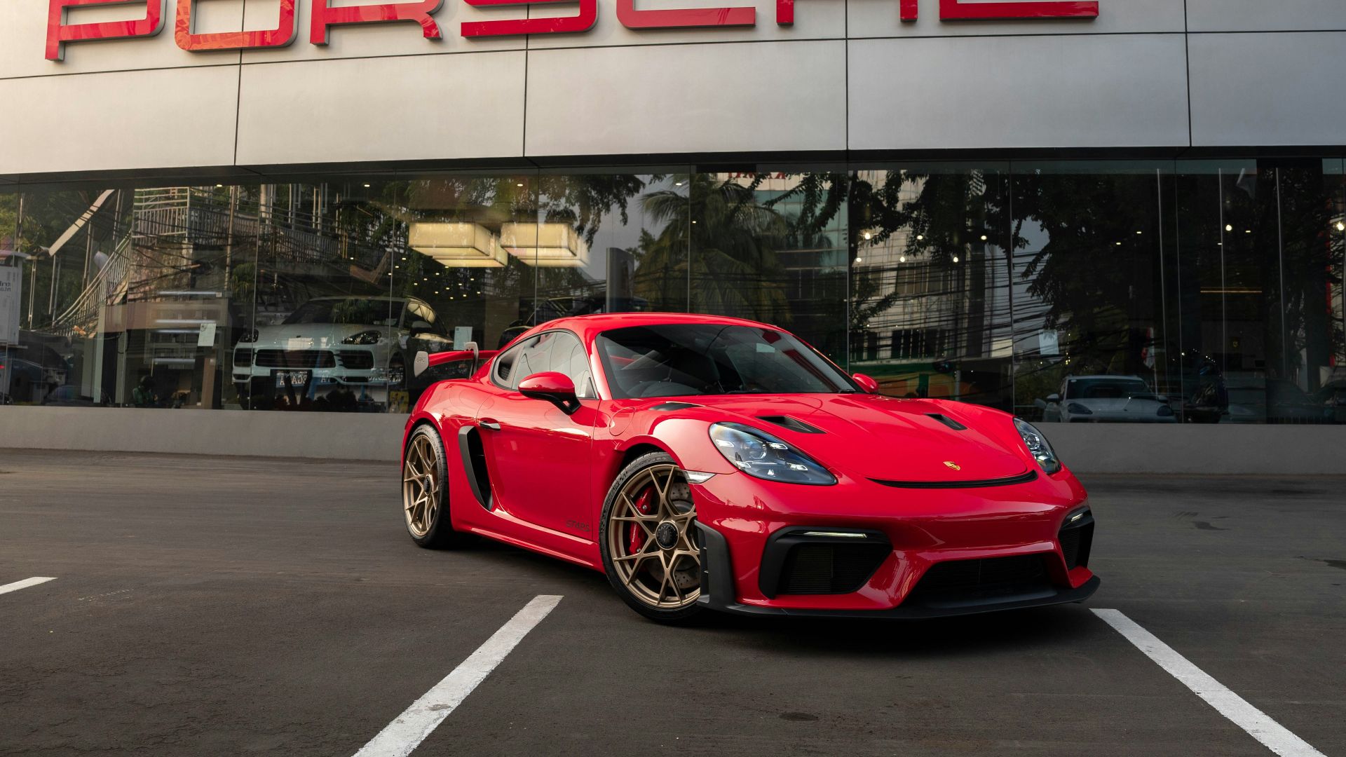 a red sports car parked in front of a porsche dealership