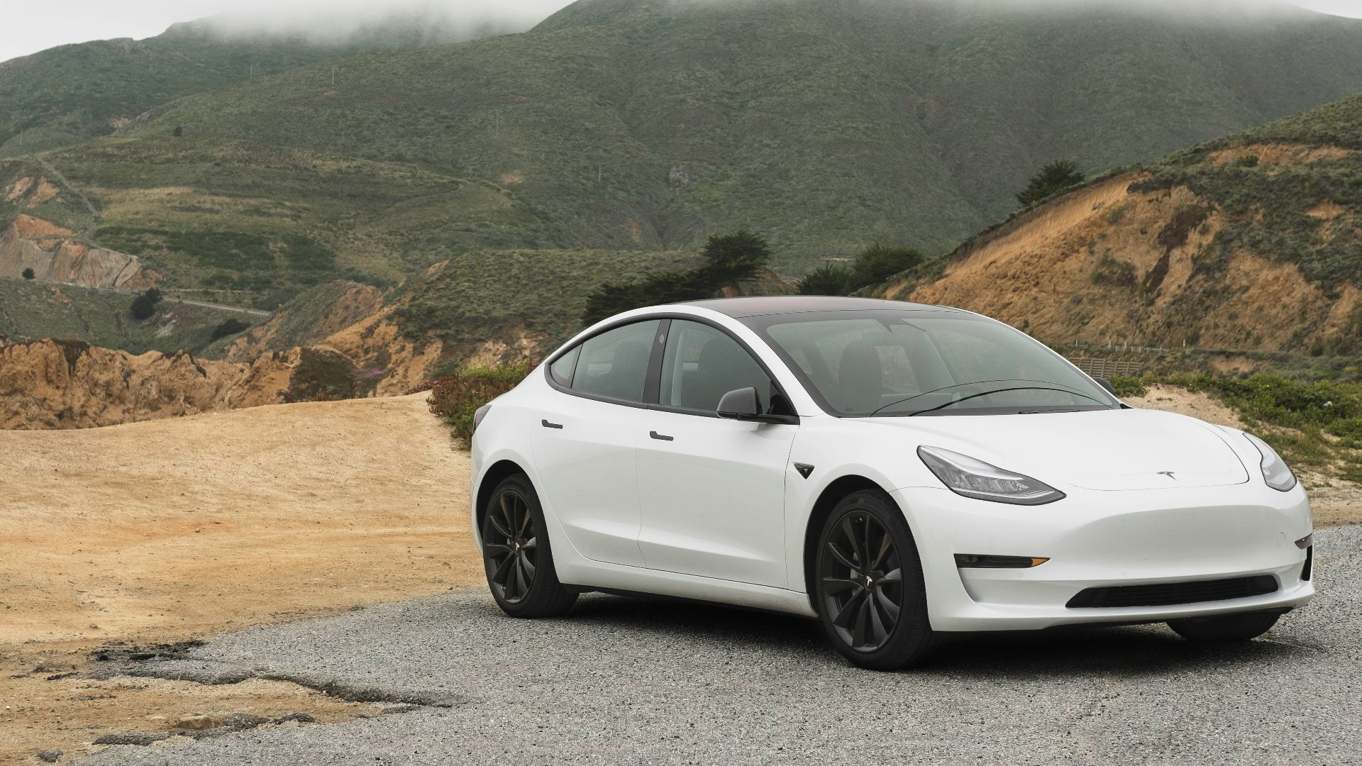 white sedan parked beside mountain during daytime