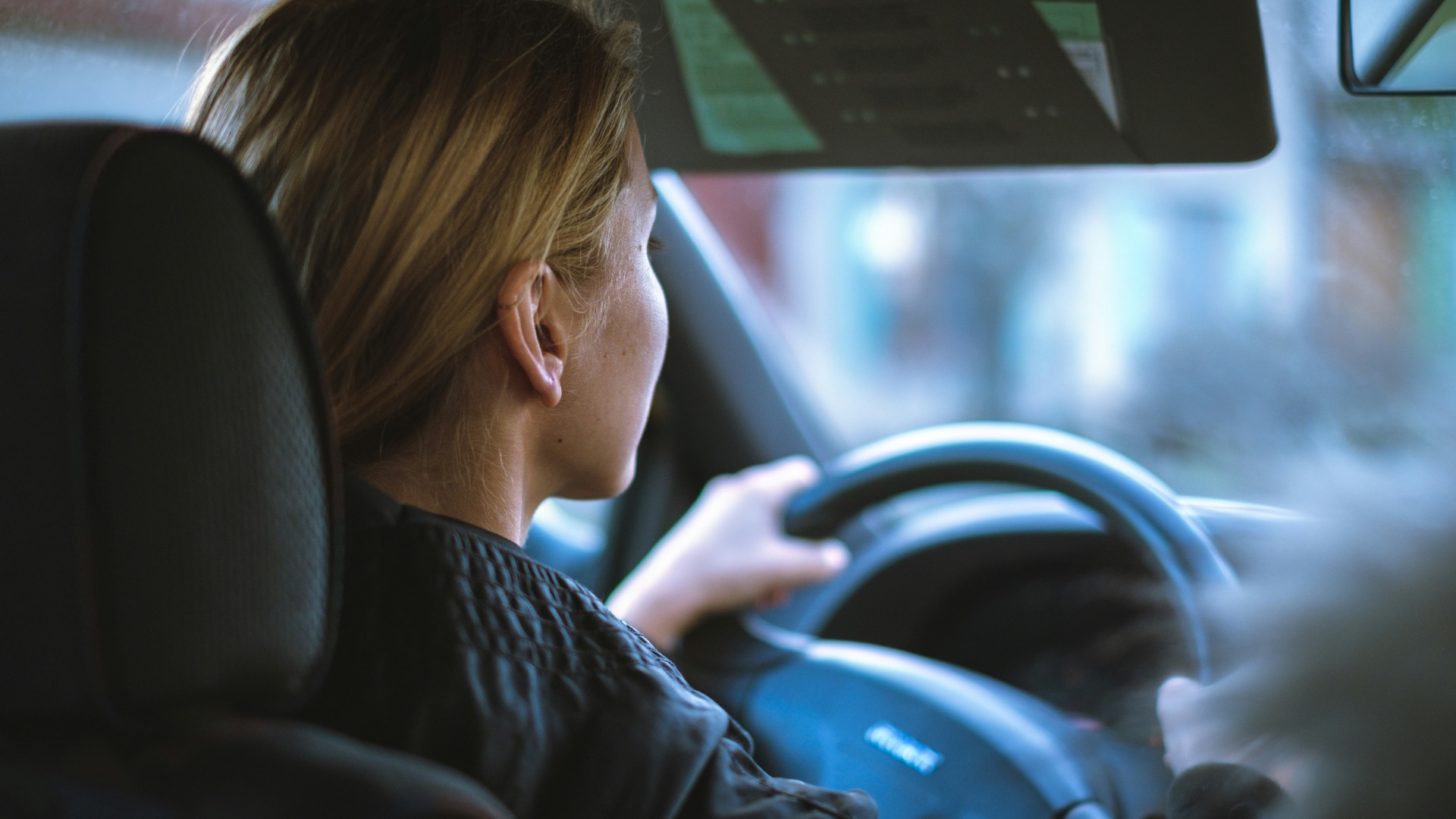 a woman sitting in a car with a steering wheel