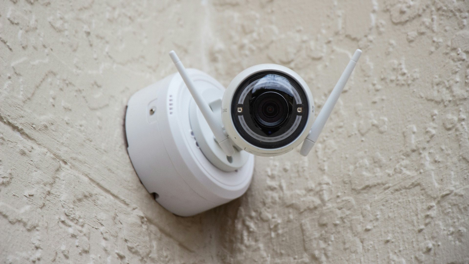 white surveillance camera hanging on wall