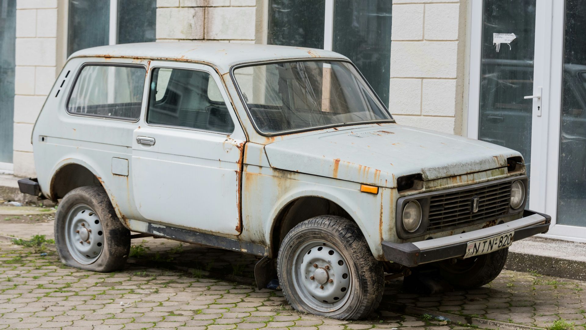 a rusted out car parked in front of a building