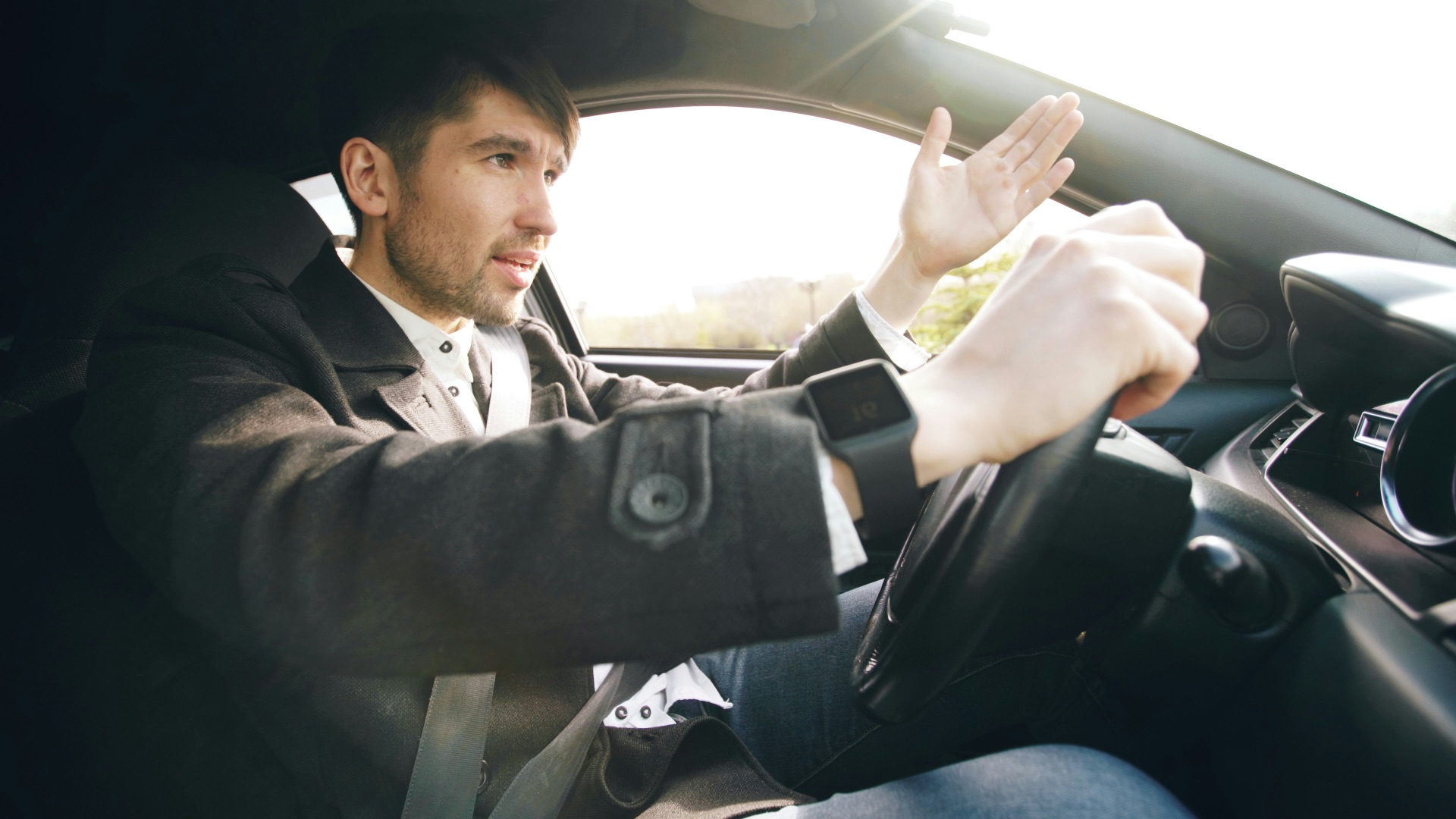 Man driving a car, gesturing with hand.