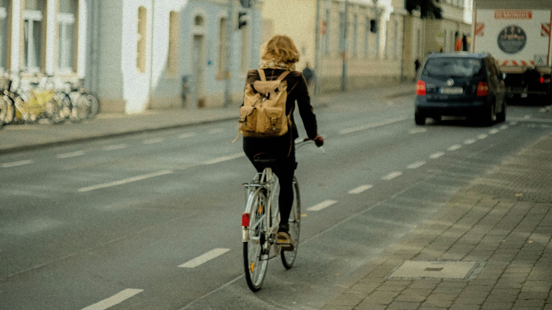 woman in black jacket riding bicycle on road during daytime