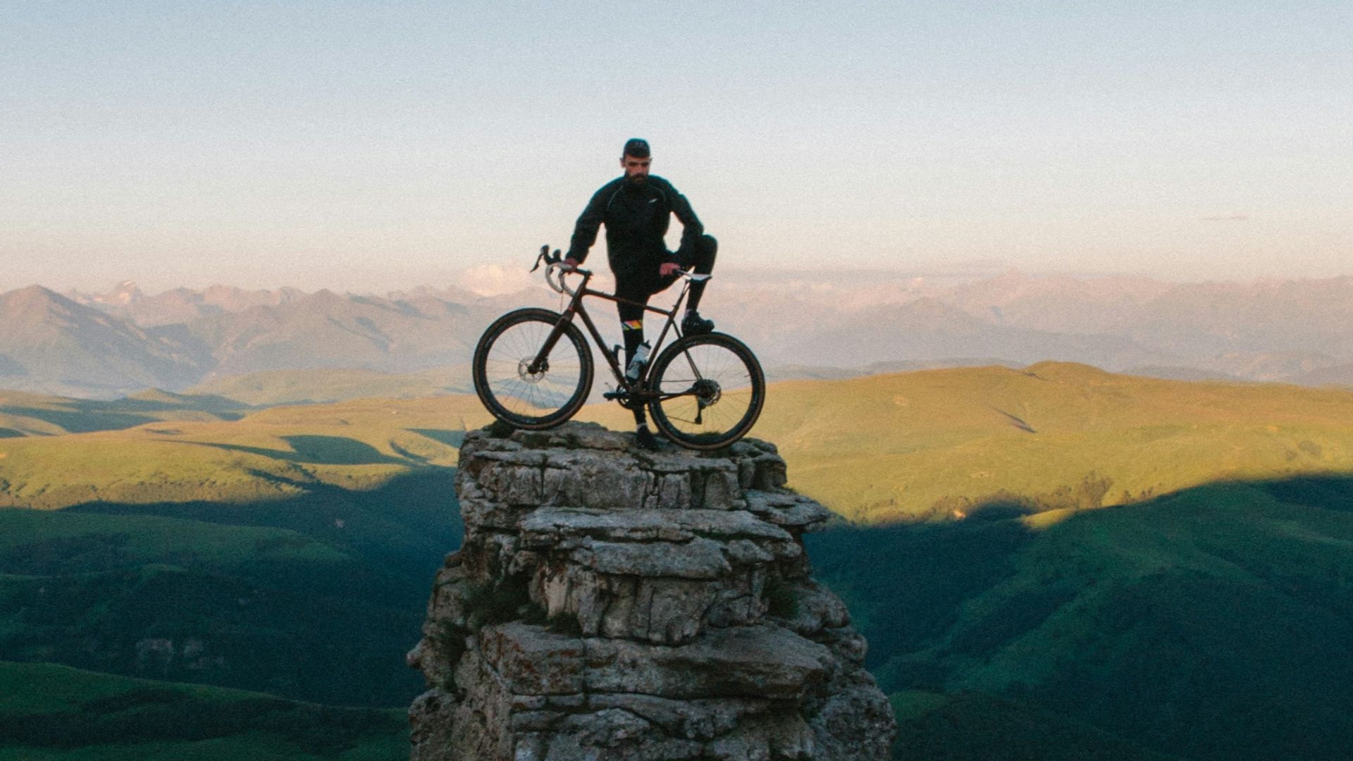 man holding bike while standing on gray mountain