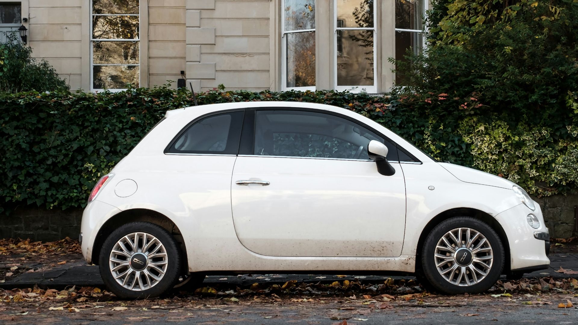 white 5 door hatchback parked beside brown concrete building during daytime
