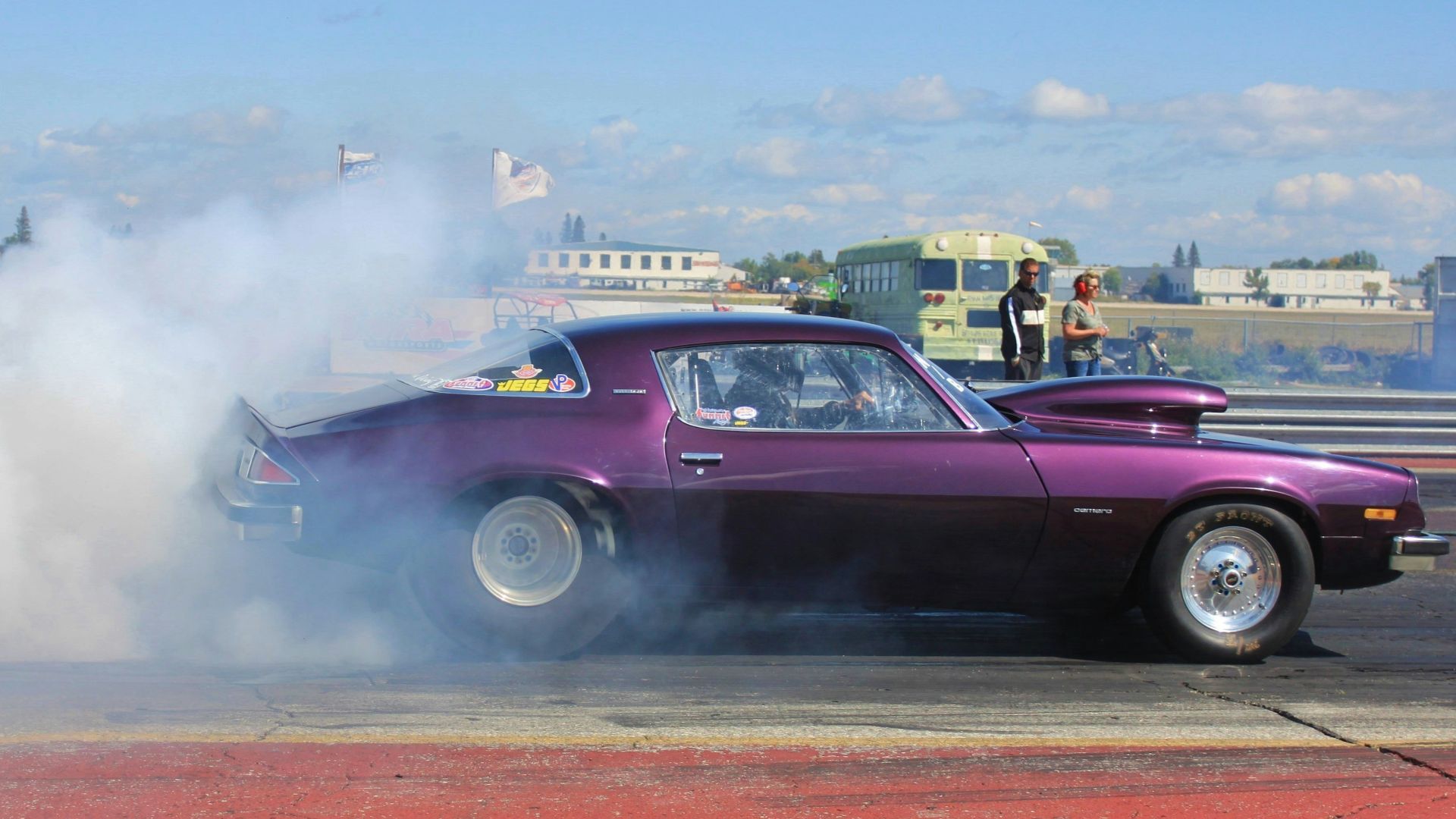purple coupe burning out on road during daytime