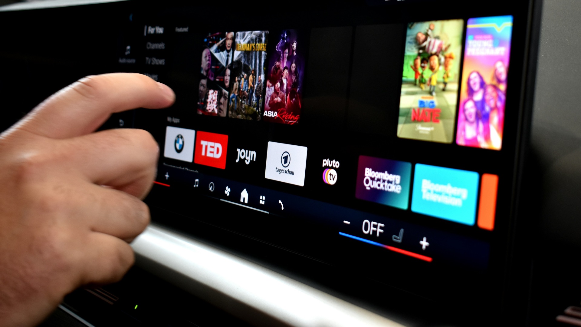 Person touching a car infotainment screen with media options.