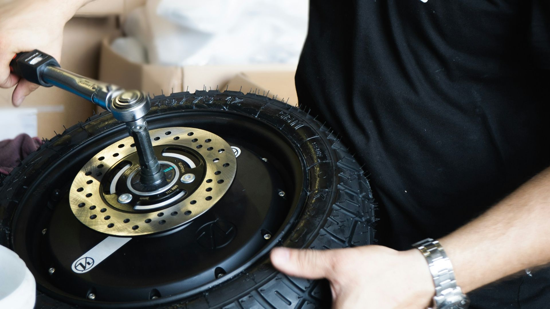 man in black crew neck t-shirt holding black wheel