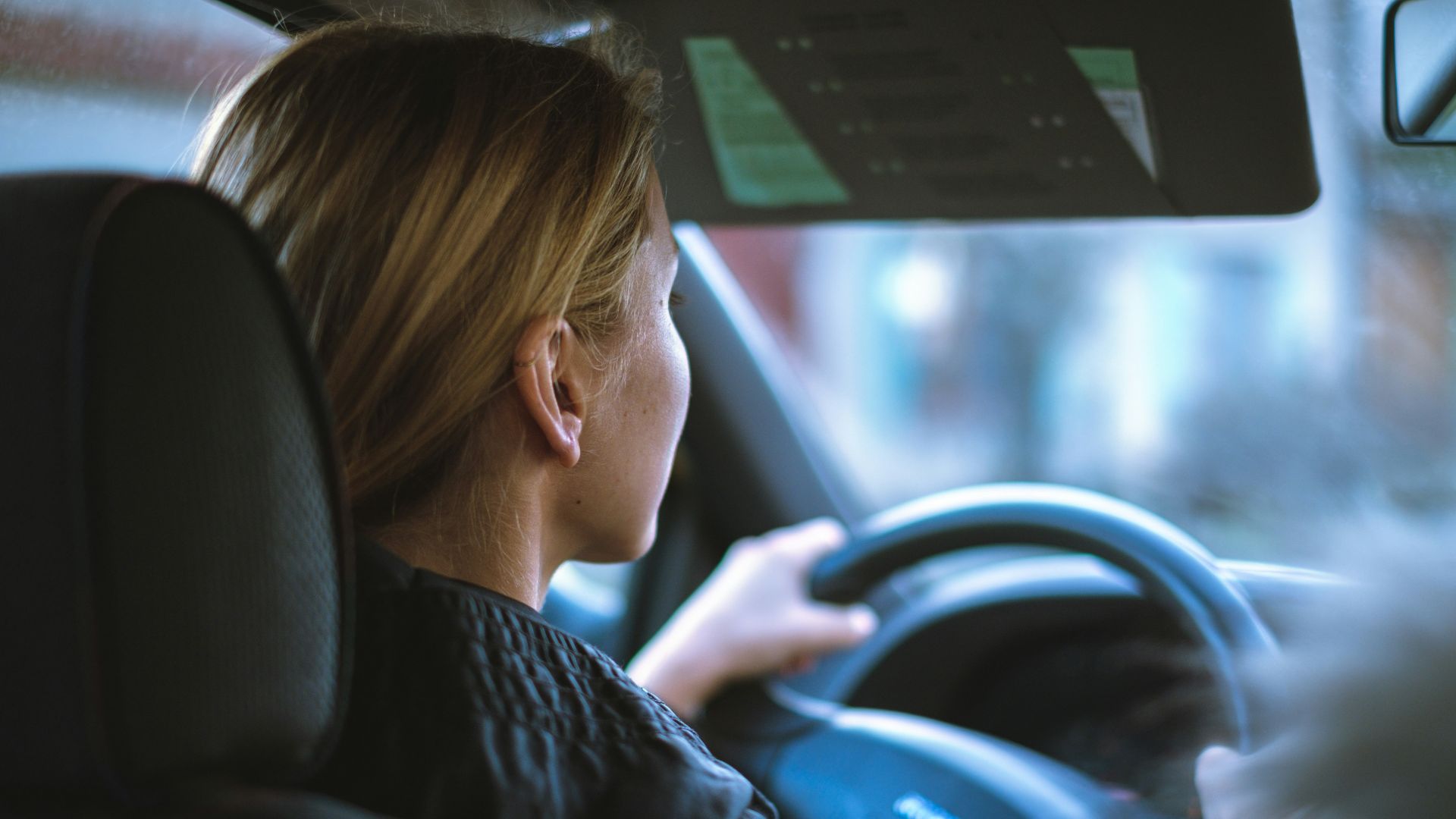 a woman sitting in a car with a steering wheel