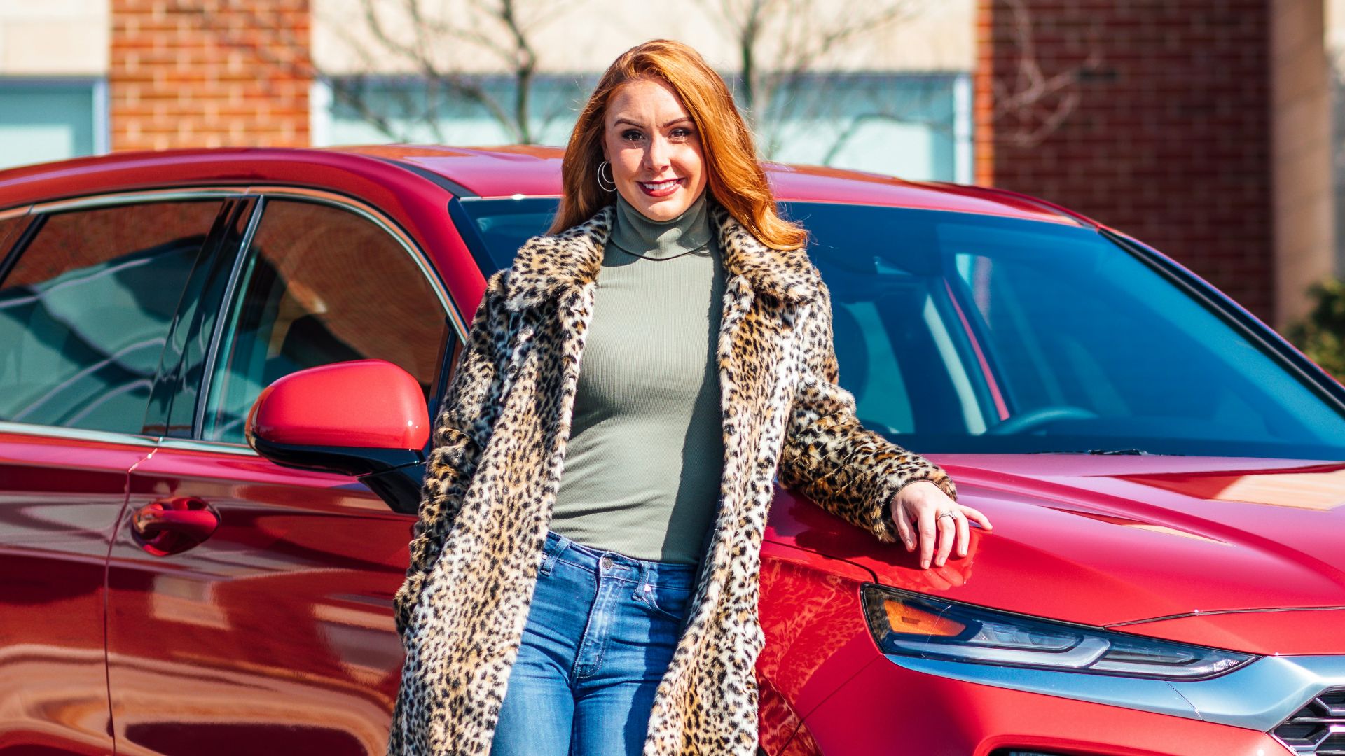 woman in white and black scarf and blue denim jeans standing beside red mercedes benz car
