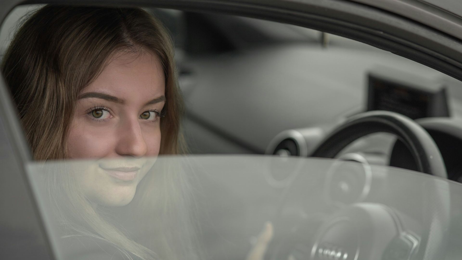 a woman sitting in a car holding a steering wheel