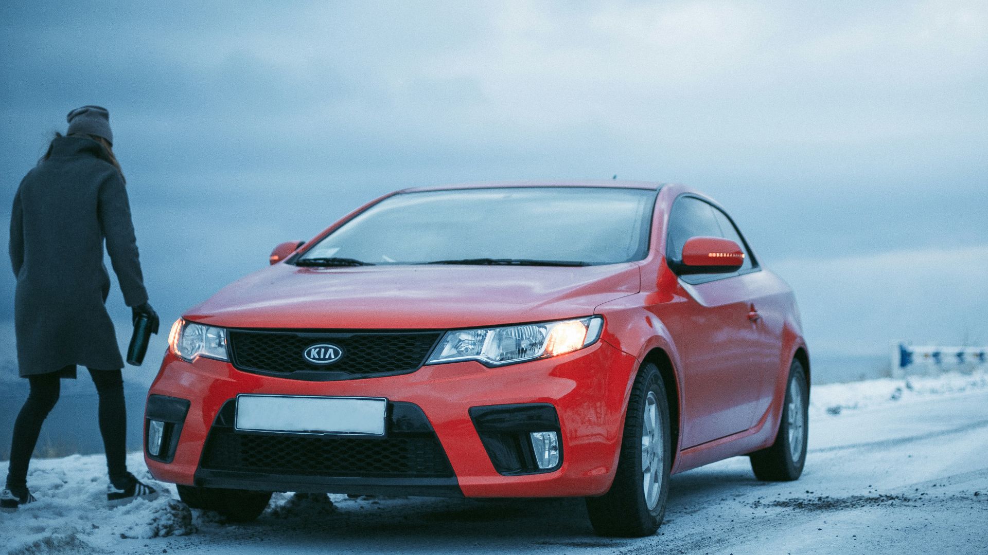 person standing beside Kia coupe