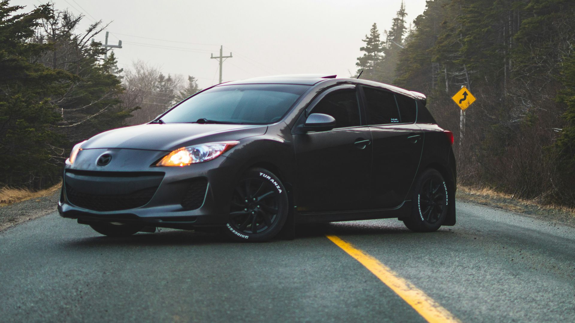 black Mazda 5-door hatchback in middle of road