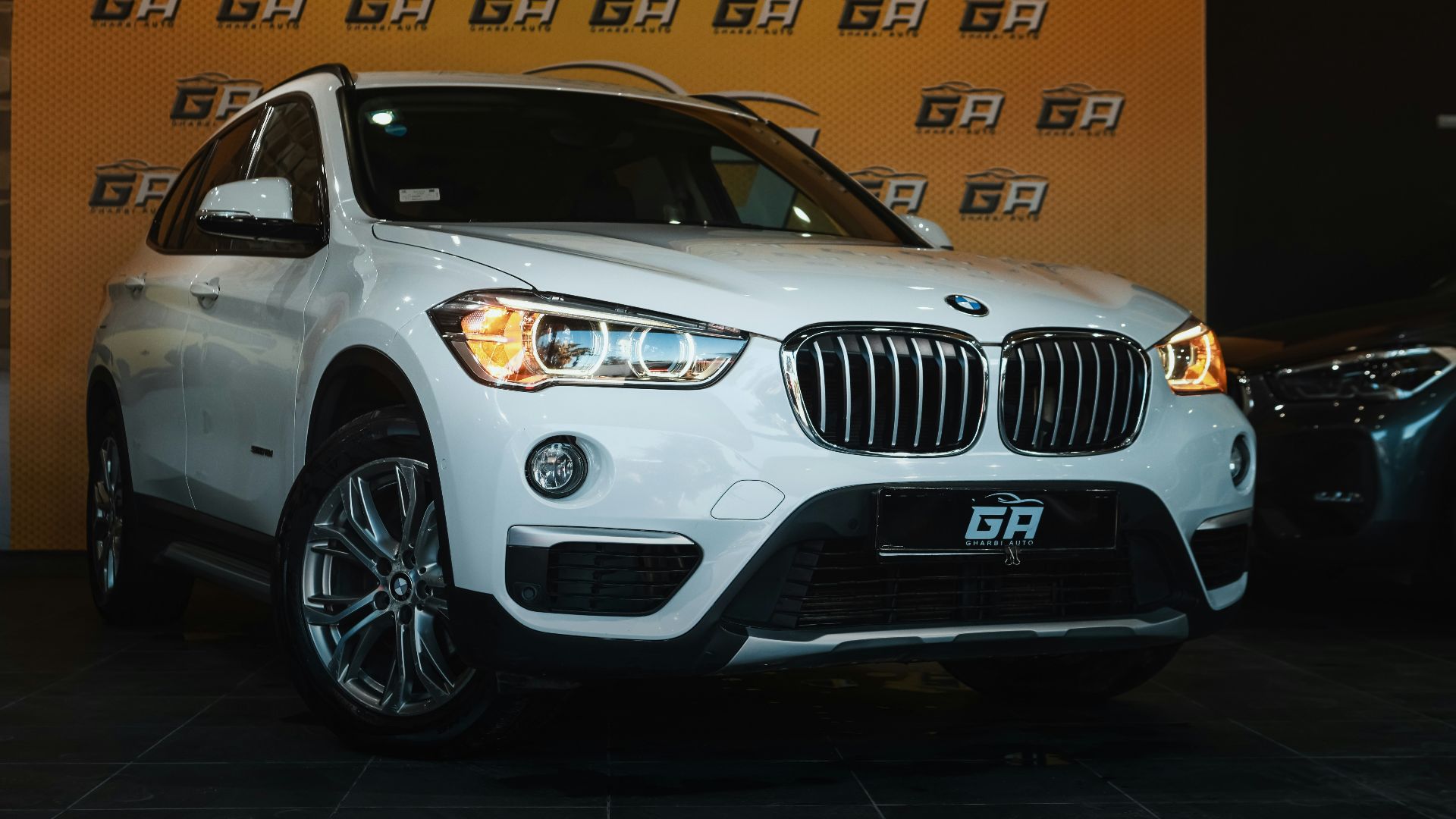 a white bmw suv parked in front of a wall