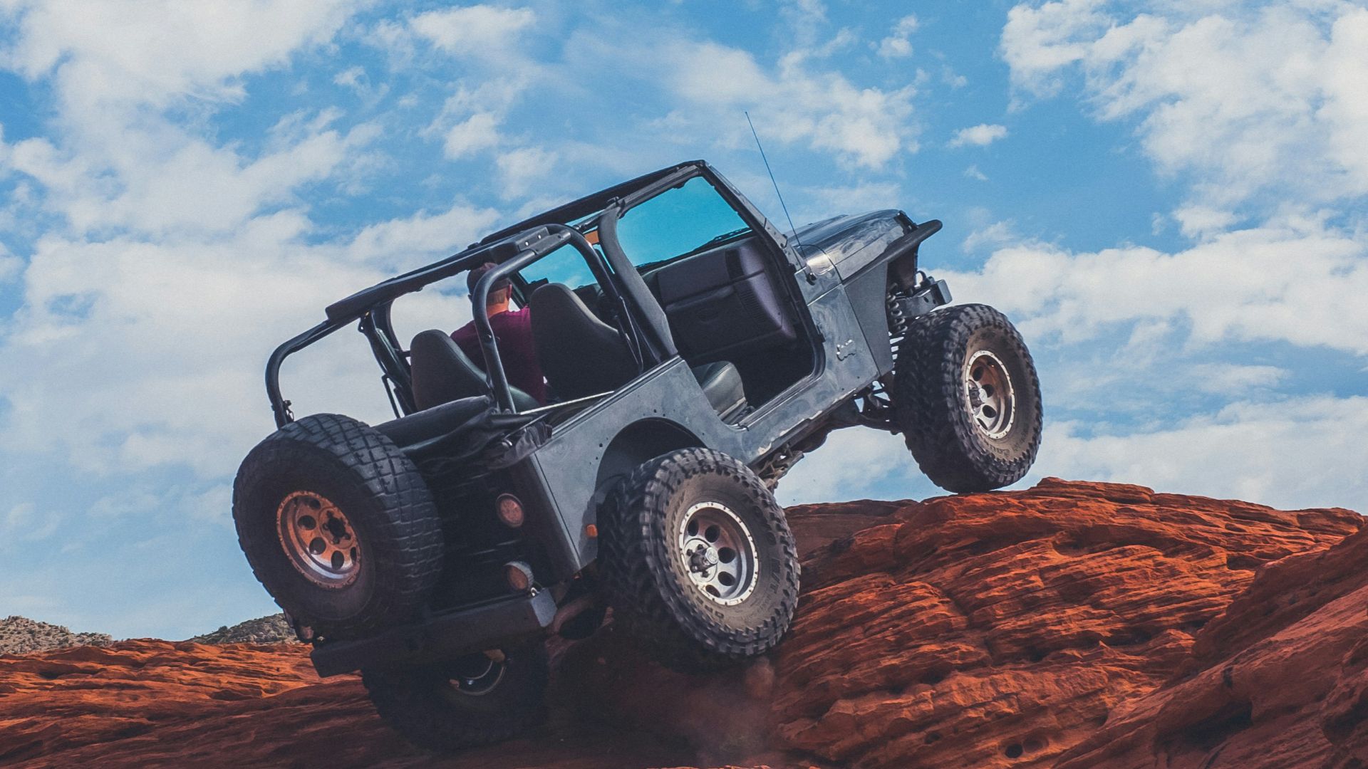 gray 4x4 vehicle climbing the rock during daytime