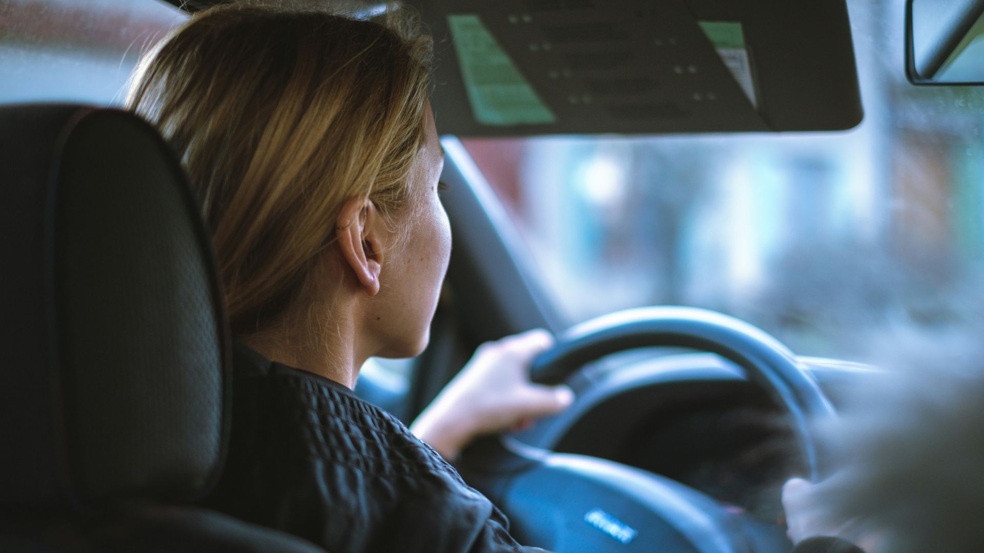 a woman sitting in a car with a steering wheel