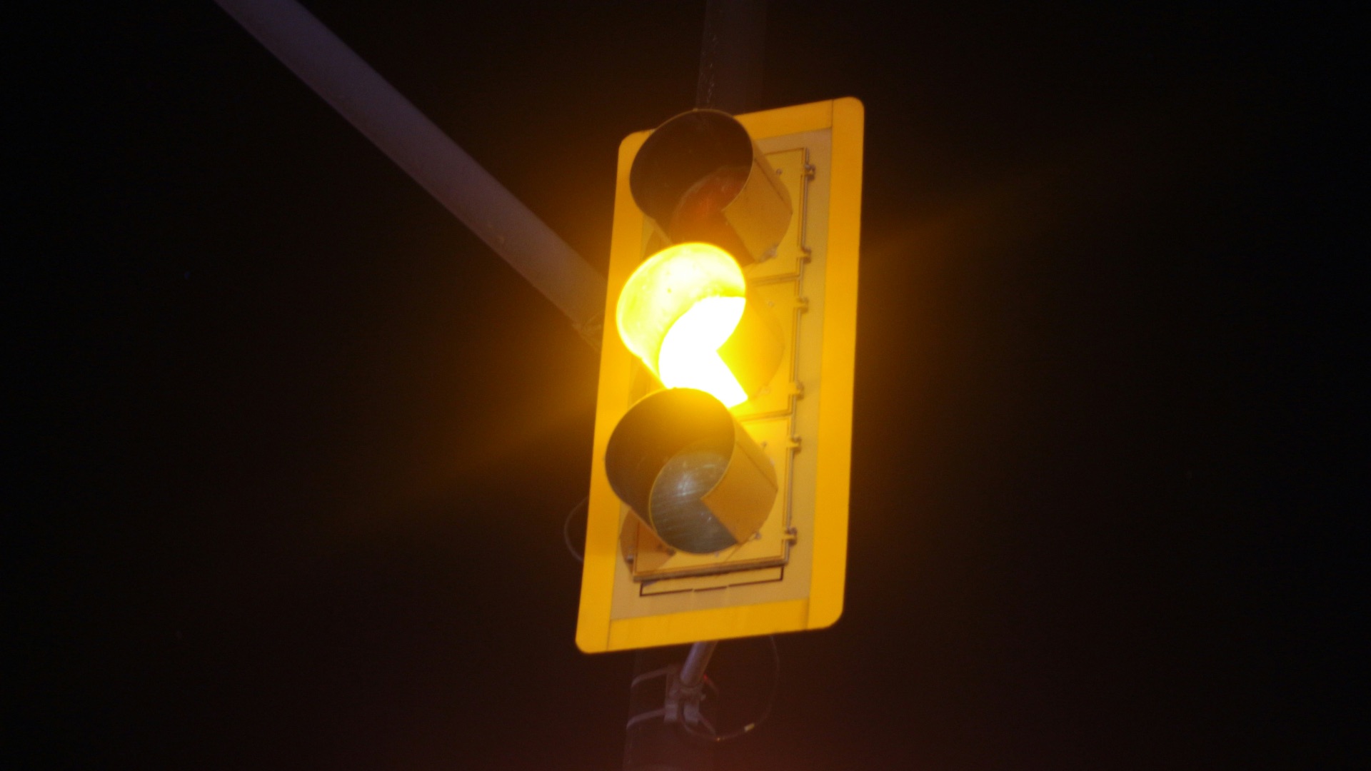 a traffic light with a yellow light hanging off of it's side