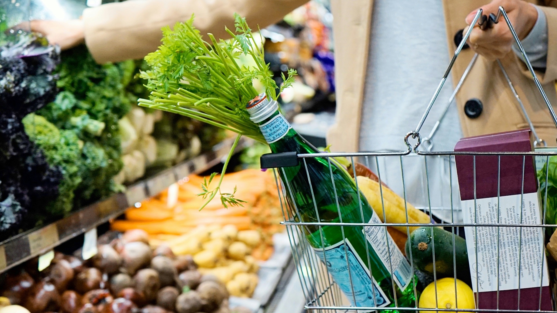 woman in white coat holding green shopping cart