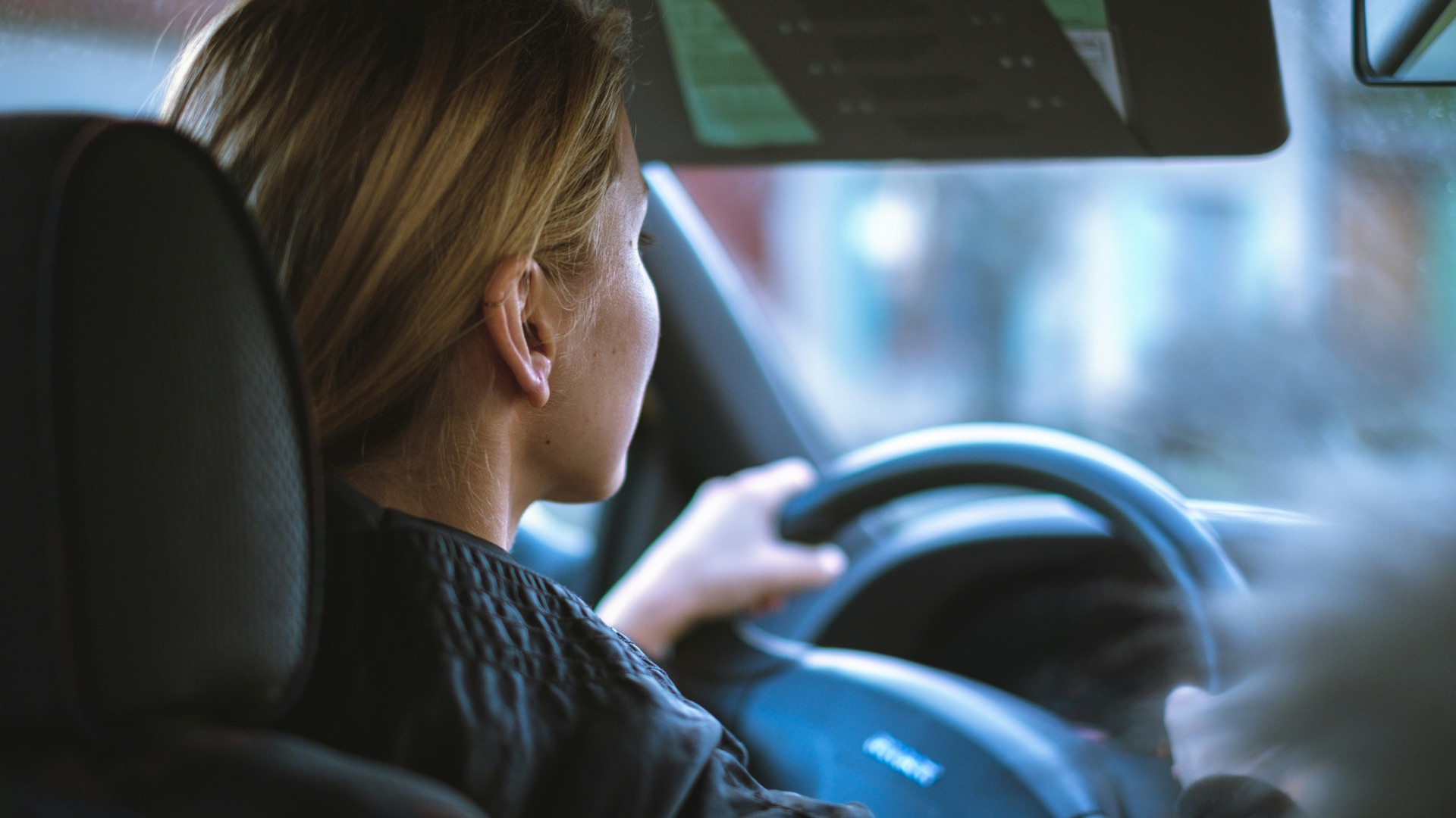 a woman sitting in a car with a steering wheel