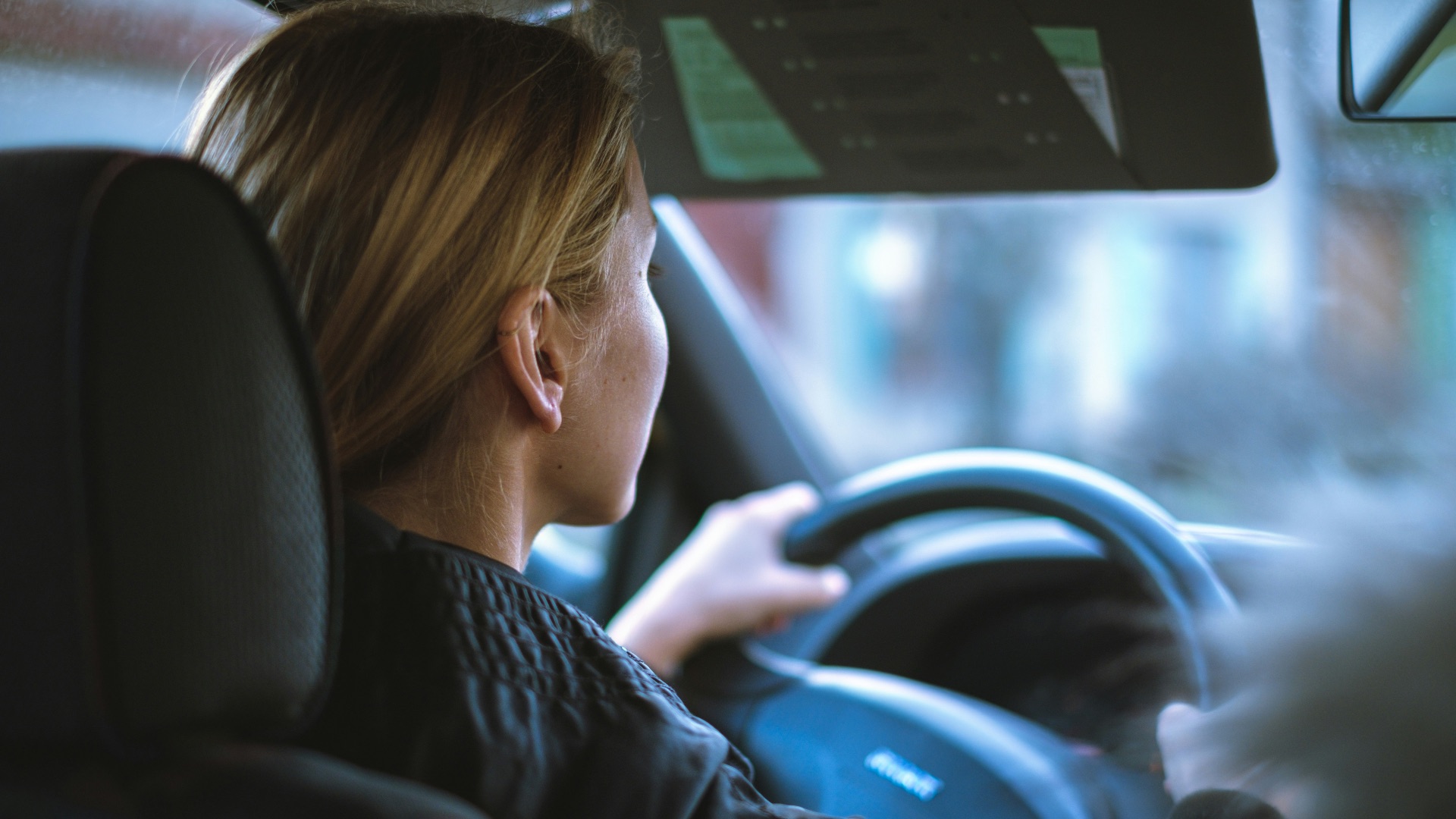 a woman sitting in a car with a steering wheel
