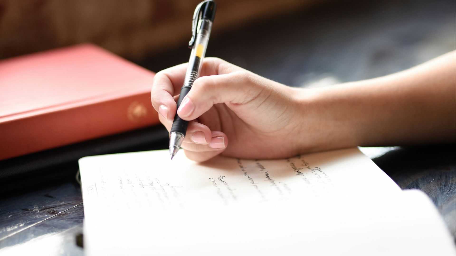 a person writing on a piece of paper with a pen