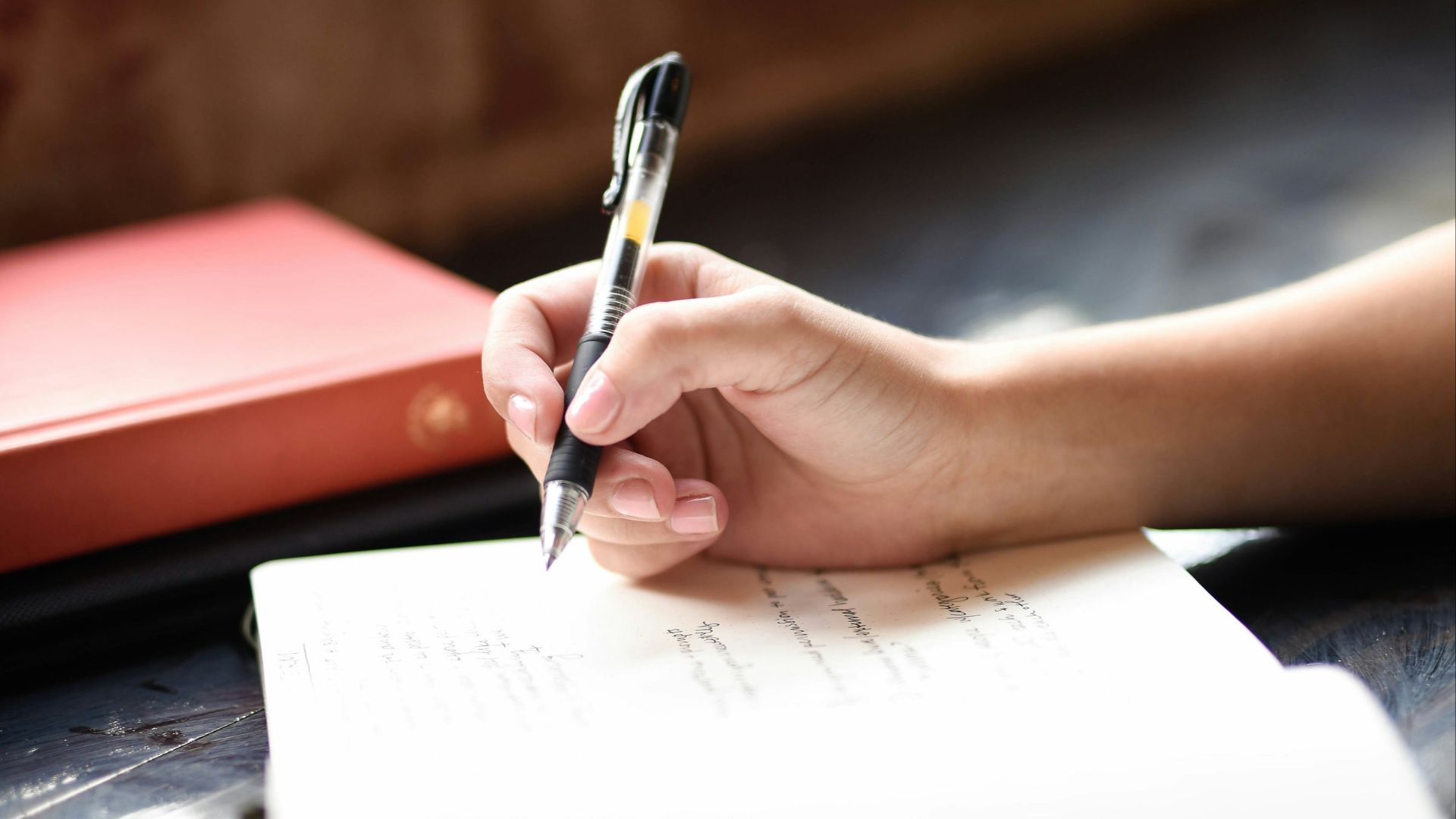 a person writing on a piece of paper with a pen