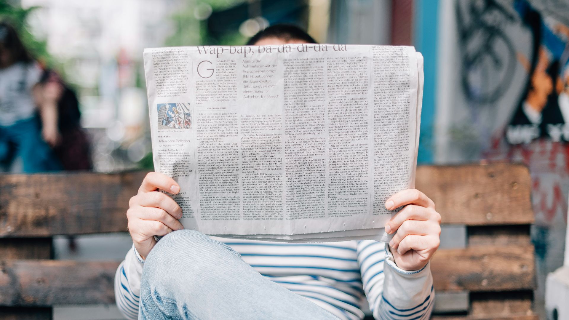 man sitting on bench reading newspaper