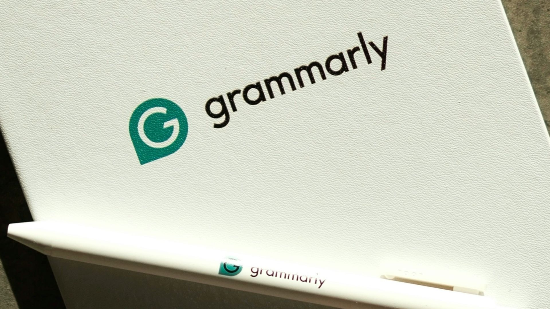 Grammarly notebook, pen, and keyboard on a desk.