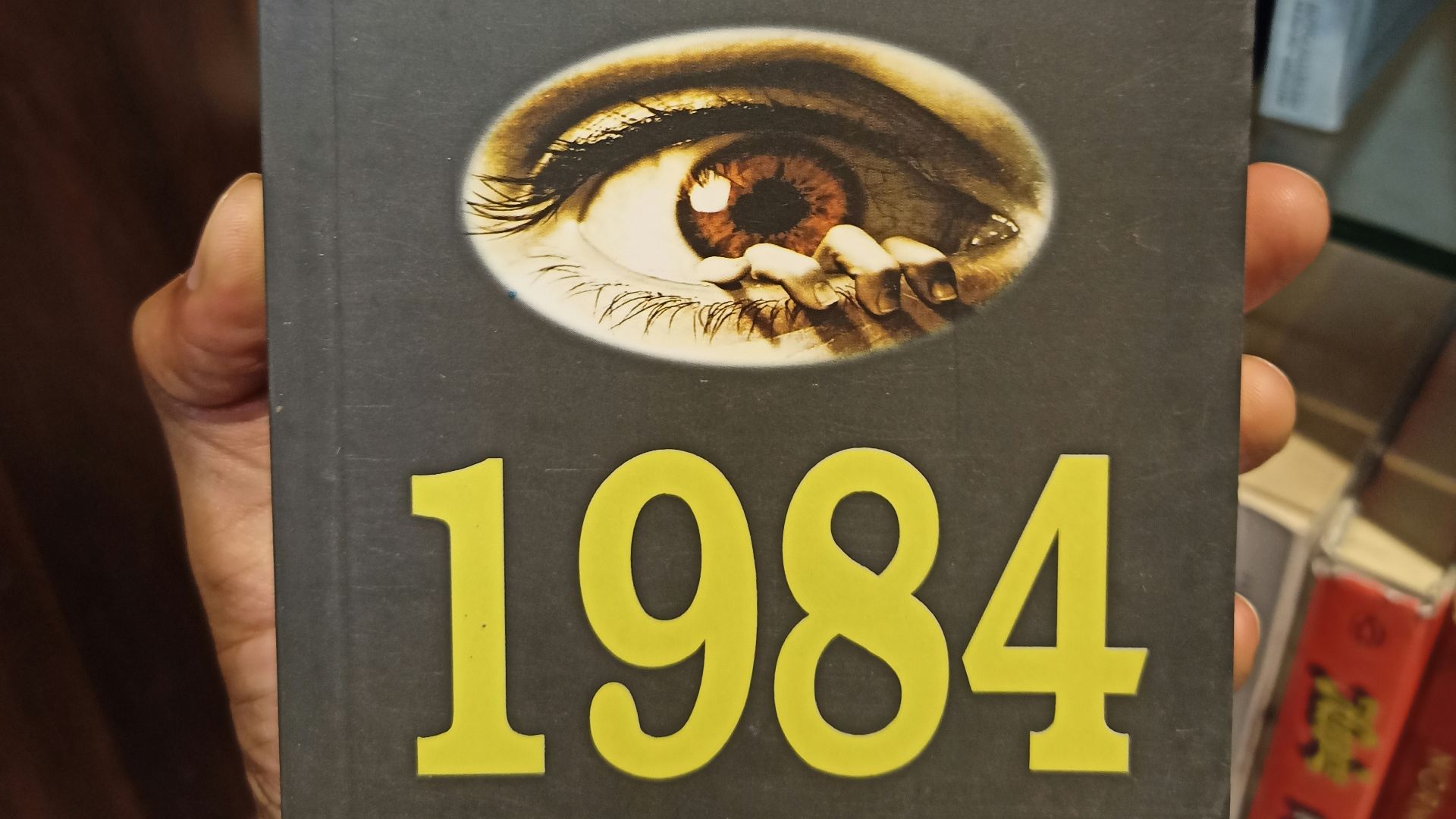 a person holding up a book in front of a book shelf