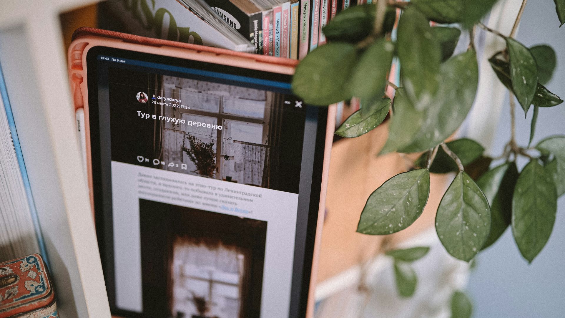 a black and white tablet on a table with a plant and books