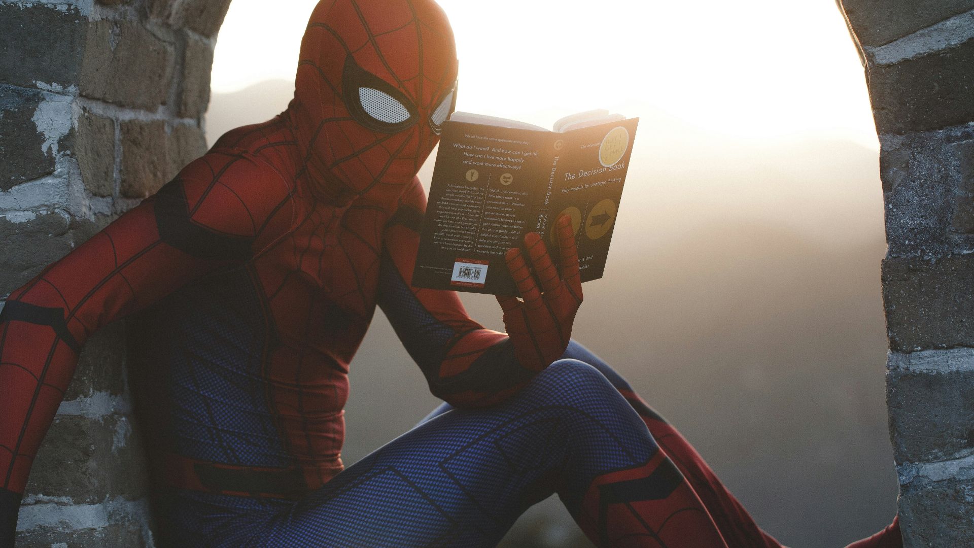 Spider-Man leaning on concrete brick while reading book