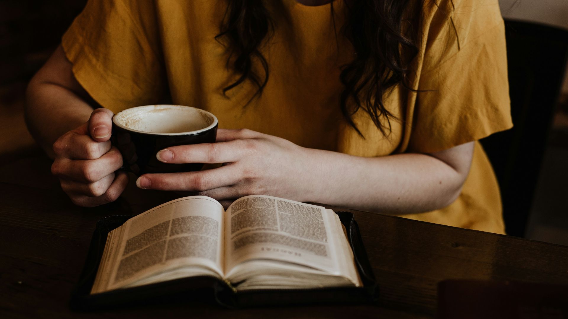 woman holding mug in front of book