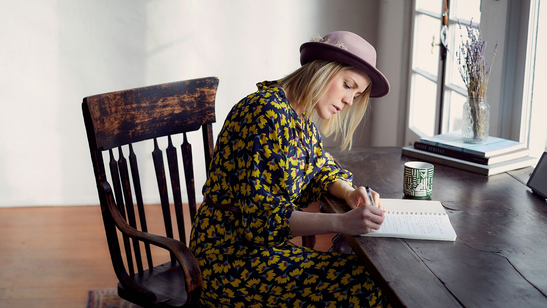woman in yellow and black floral dress sitting on brown wooden chair