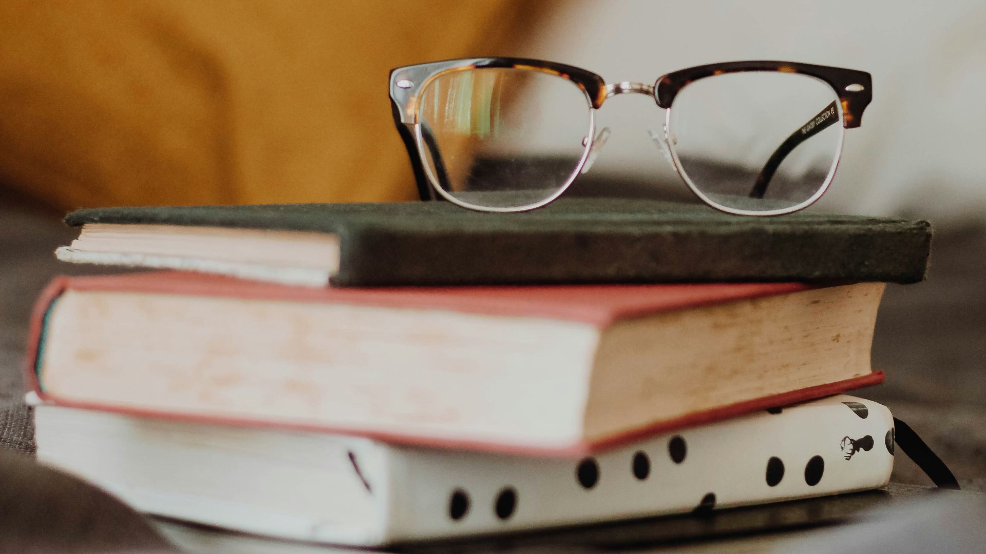 club master eyeglasses on pile of three books