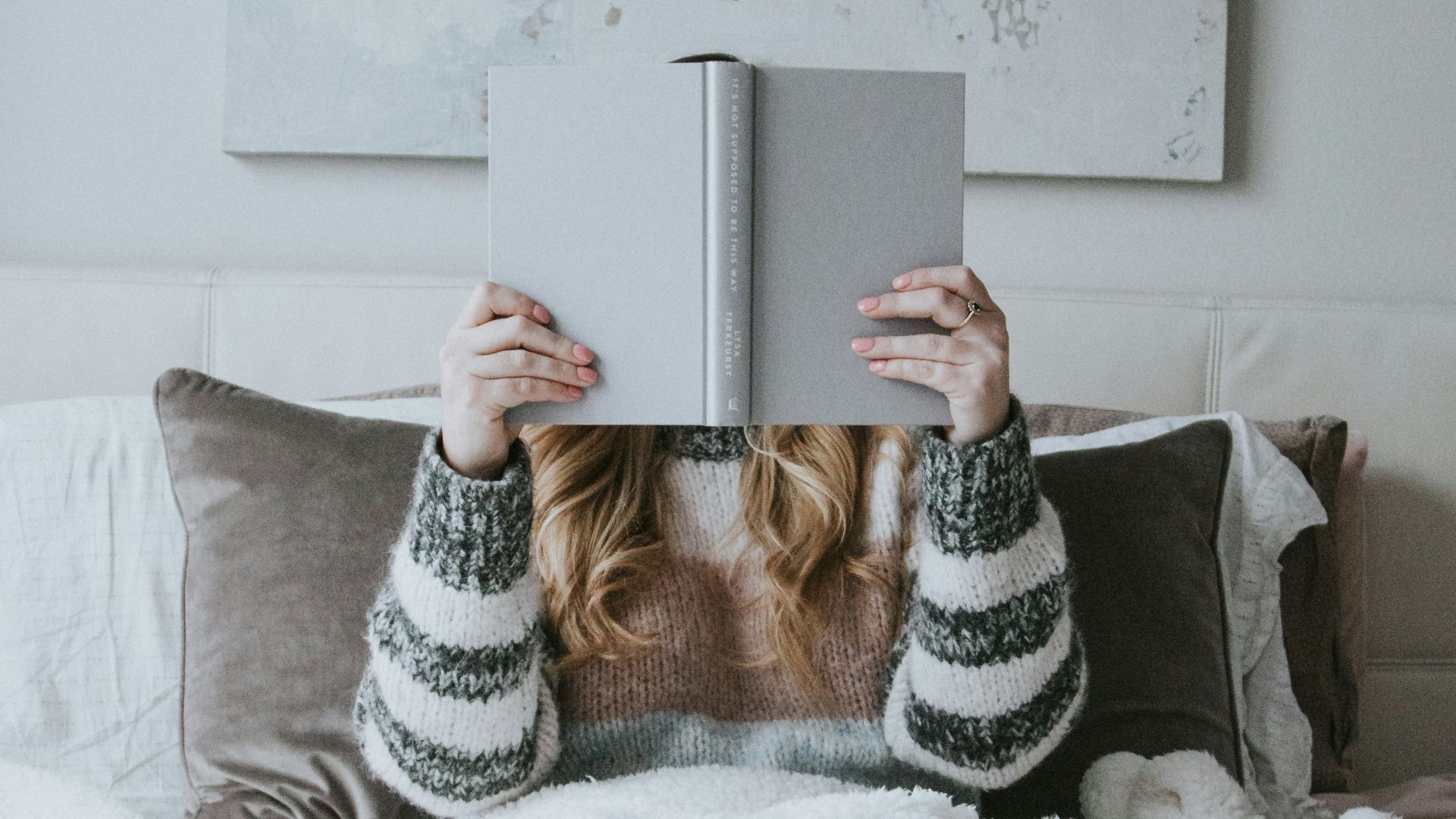woman sitting on bed while holding book