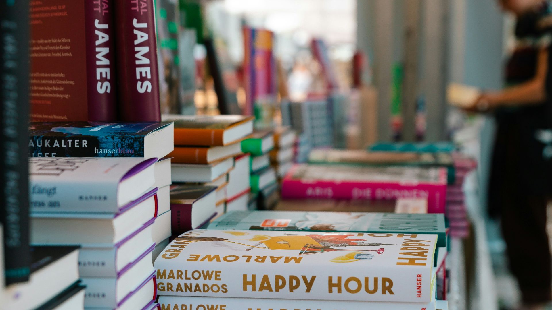 A number of books on a table with people in the background