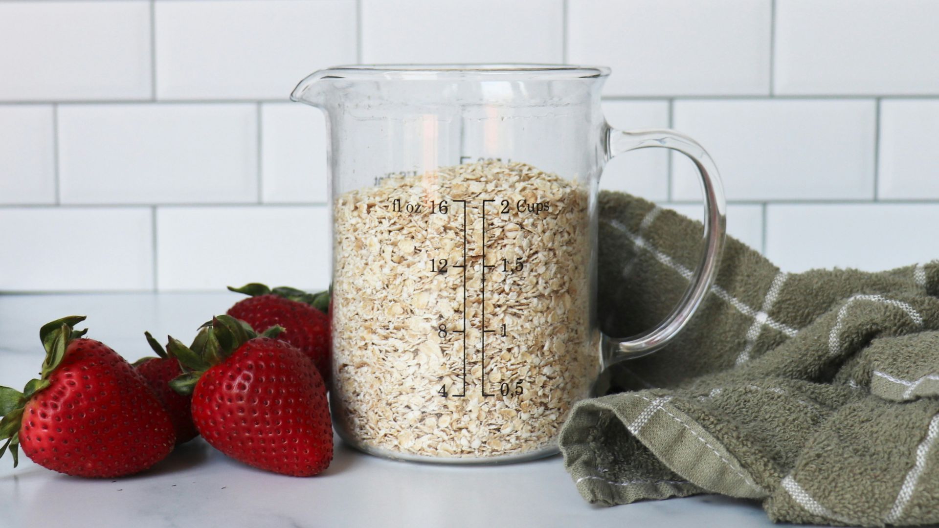 strawberries on white ceramic bowl beside clear glass pitcher