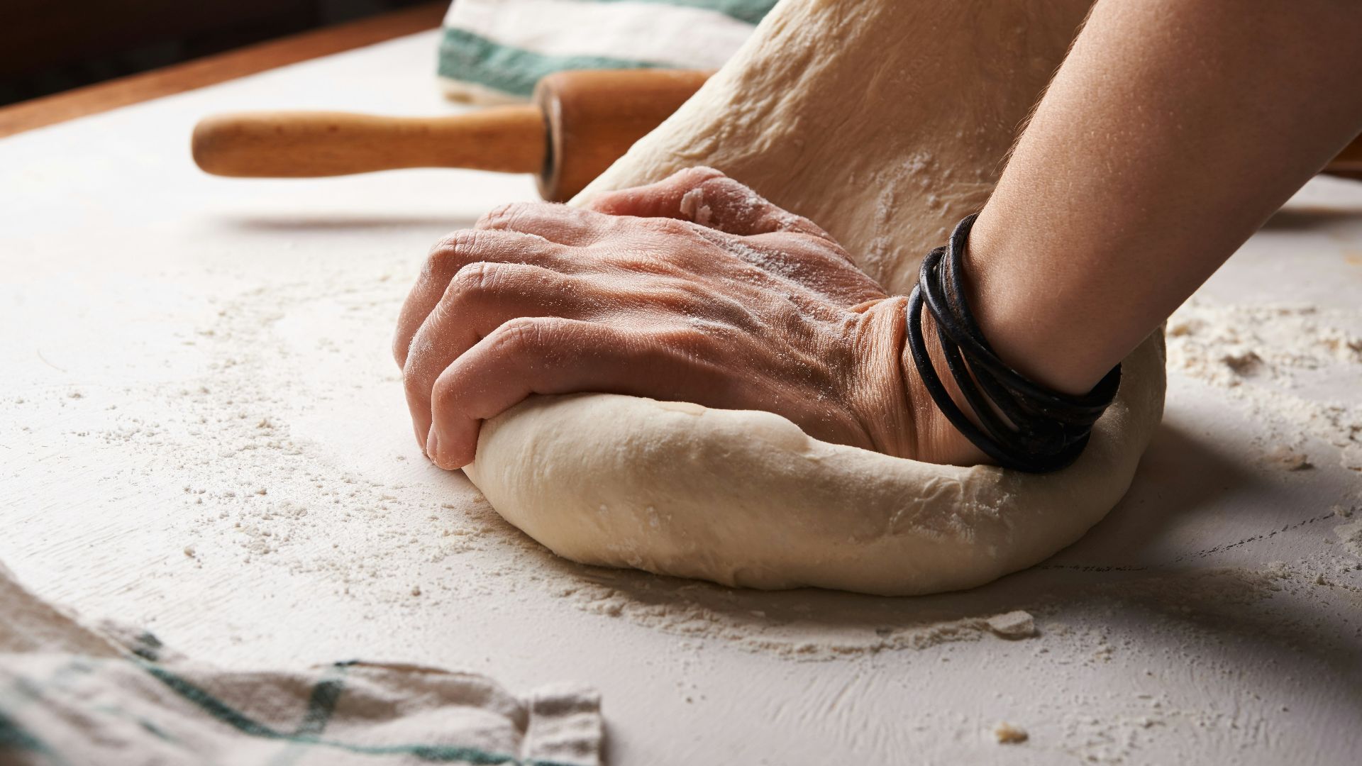 person making dough beside brown wooden rolling pin
