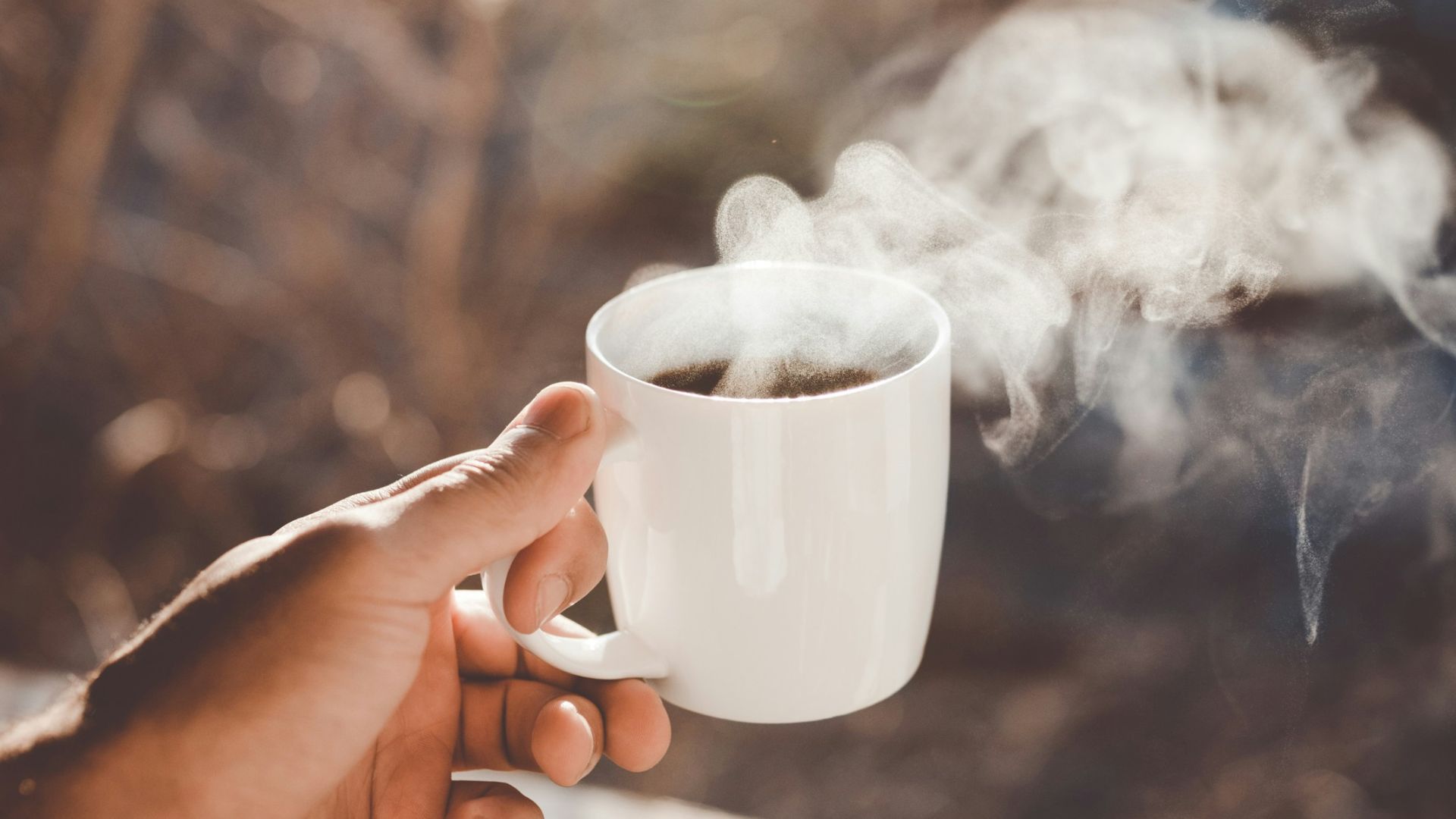 person holding white ceramic cup with hot coffee