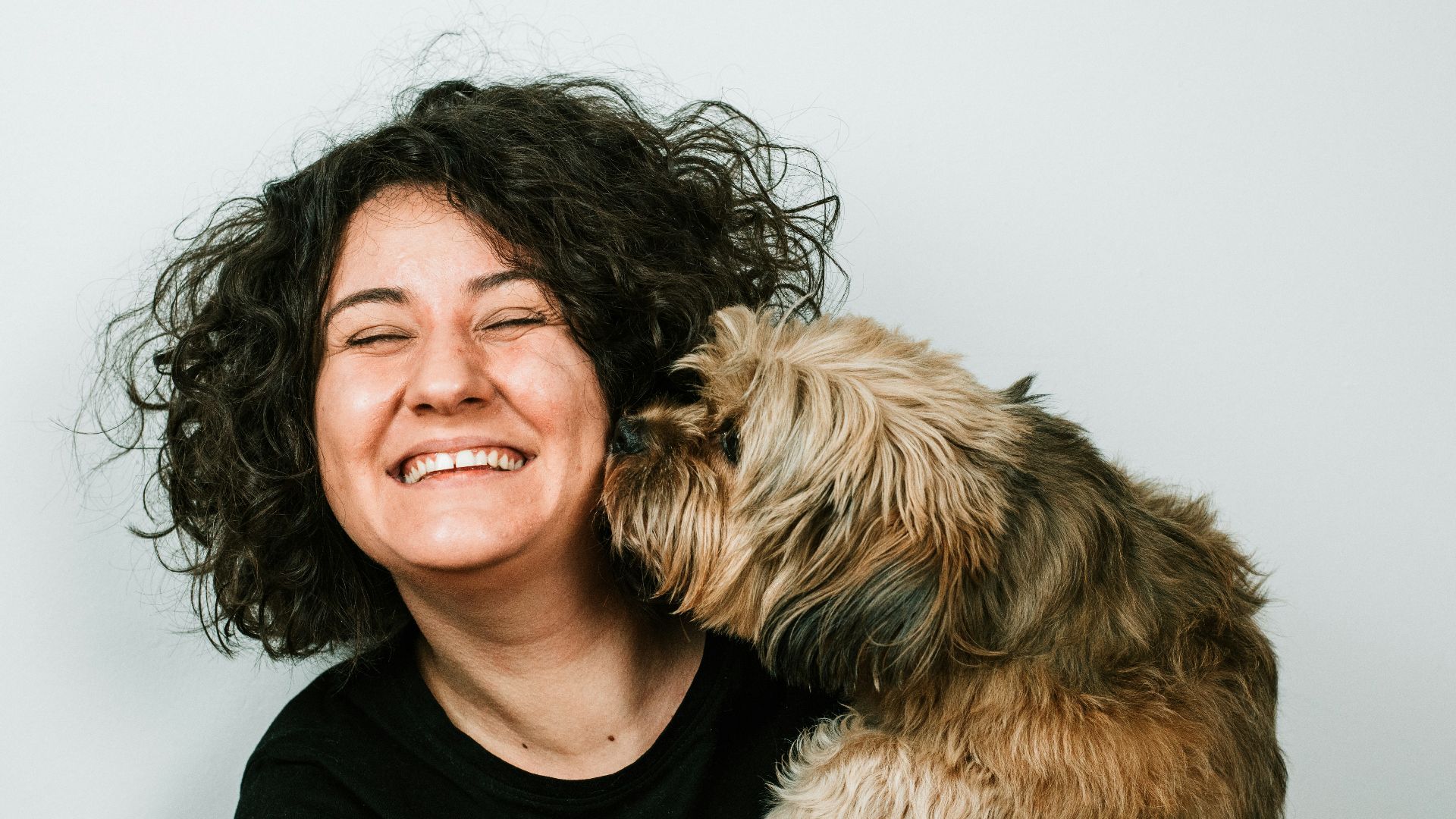dog kissing woman in black crew-neck shirt