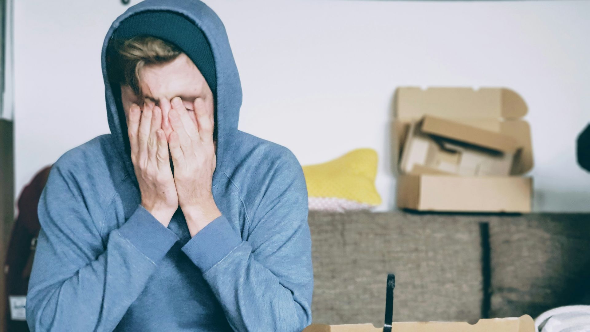 man covering face with both hands while sitting on bench