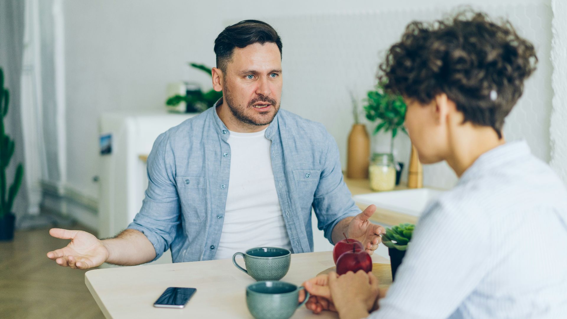 a man sitting at a table talking to a woman
