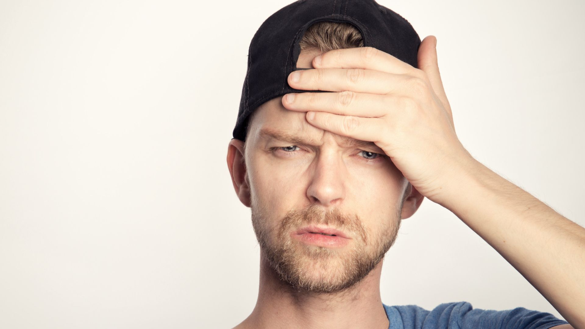 man in blue crew neck shirt covering his face