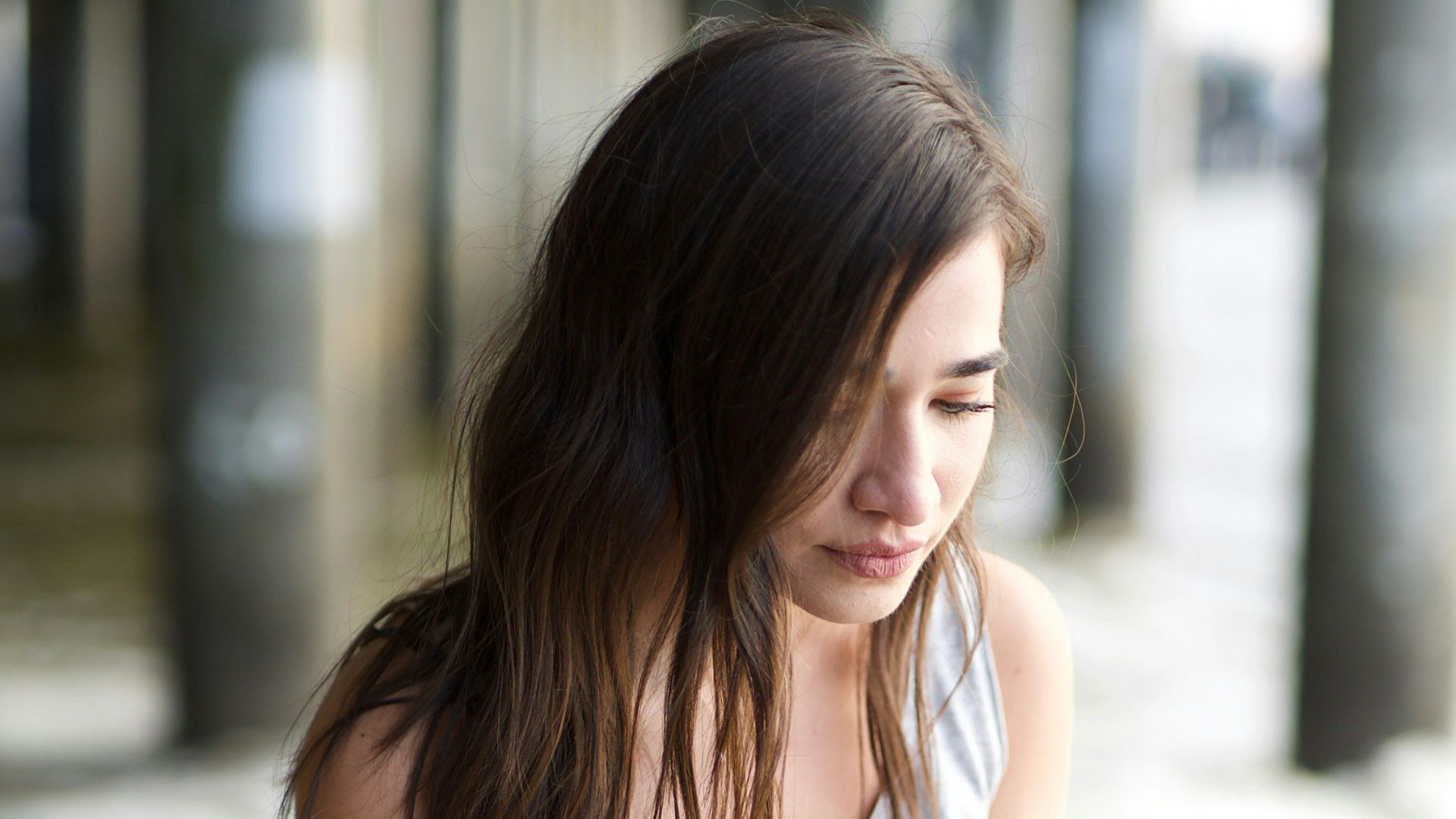 woman in white tank top and blue denim jeans sitting on concrete floor during daytime
