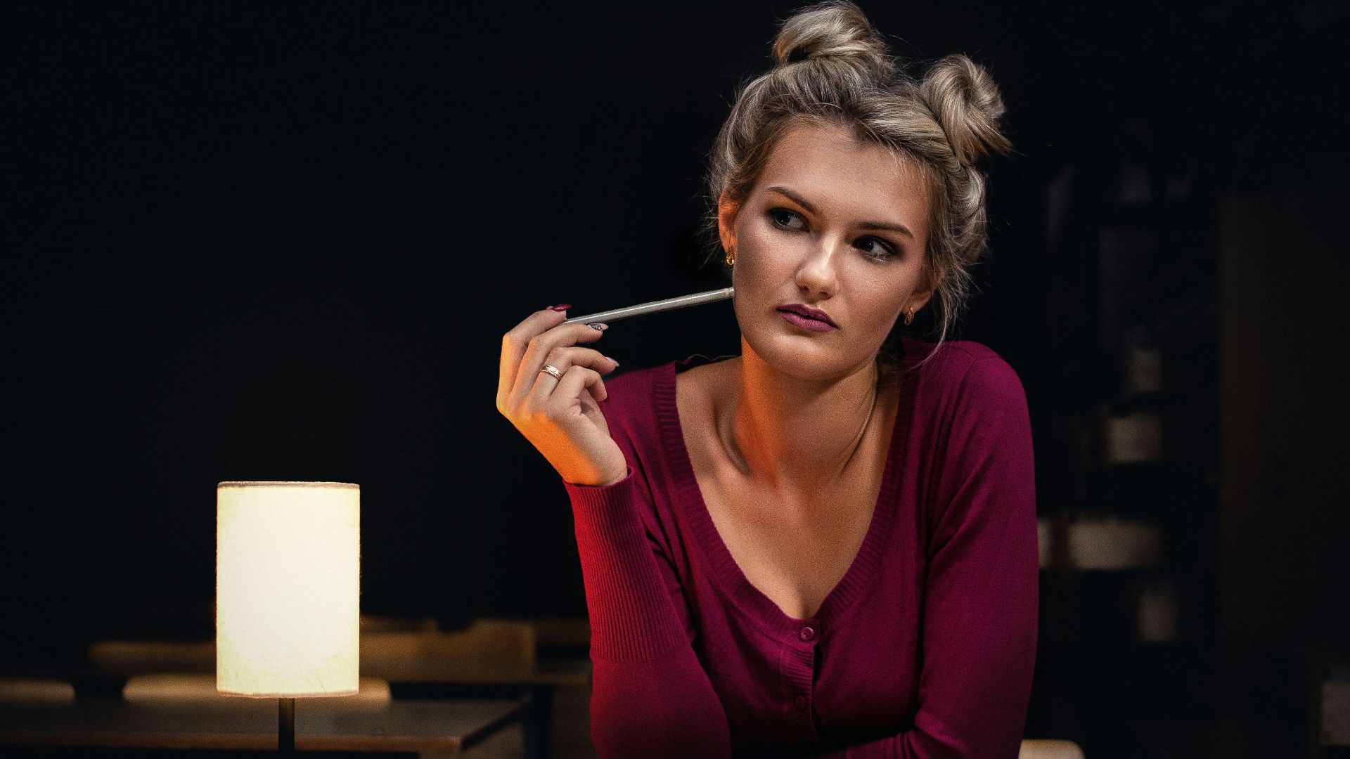 woman sitting beside opened book holding pencil