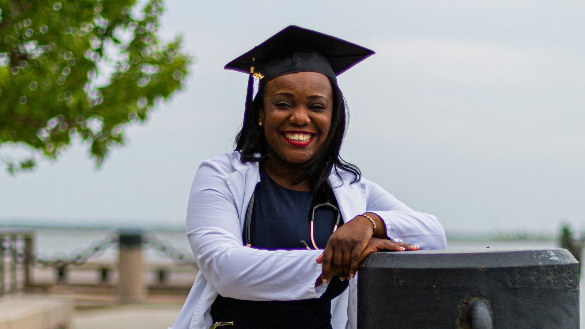 a woman in a graduation gown leaning against a chain